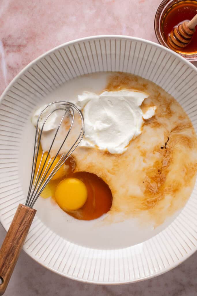 Wet ingredients for greek yogurt muffins  in a small bowl with a whisk.