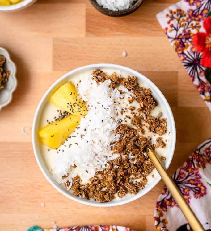 Pina colada smoothie bowl topped with pineapple, coconut, and granola.