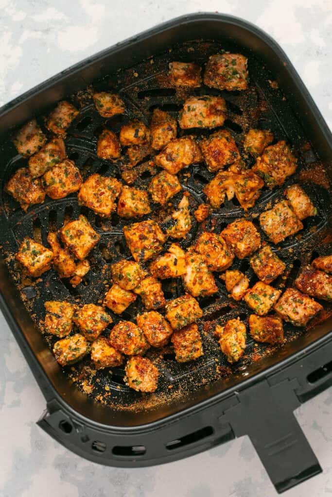 Cooked salmon bites in an air fryer basket.