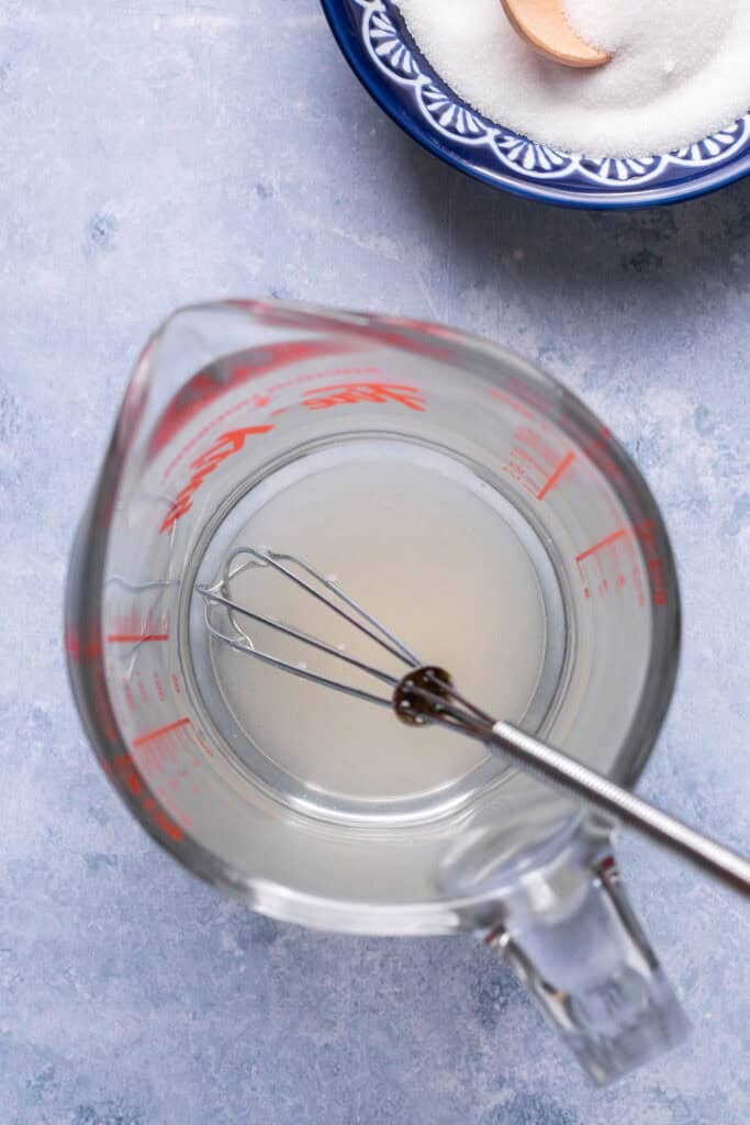 Vinegar for sushi in a glass measuring cup with a whisk.