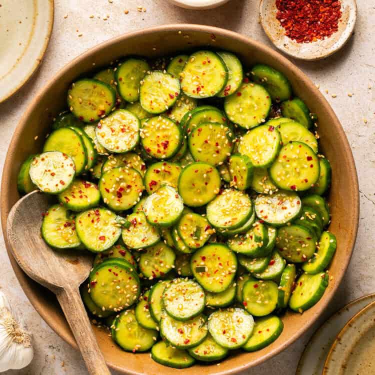 Asian Cucumber Salad in a serving bowl with a wooden spoon.