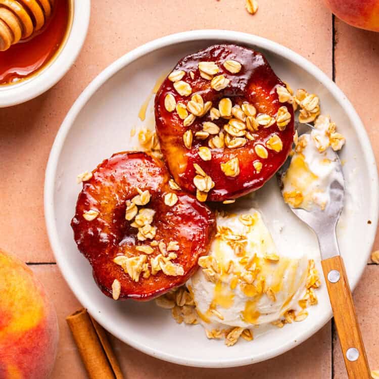 Air fryer peaches topped with granola wth a vanilla ice cream on a plate.
