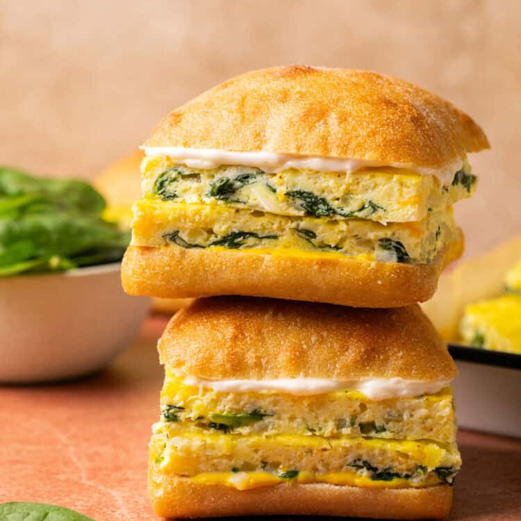 Cheesy Spinach Two Sheet Pan Eggs sandwiches on ciabatta bread stacked vertically.