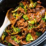 Crockpot Mongolian Beef and Brooccoli in a crock pot with a wooden spoon.