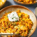Elote Ground Turkey Skillet topped with sour cream on a plate with a fork.
