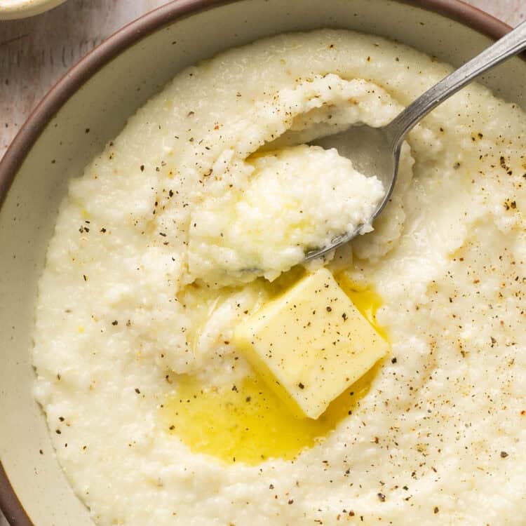 Grits topped with butter in a bowl with spoon.