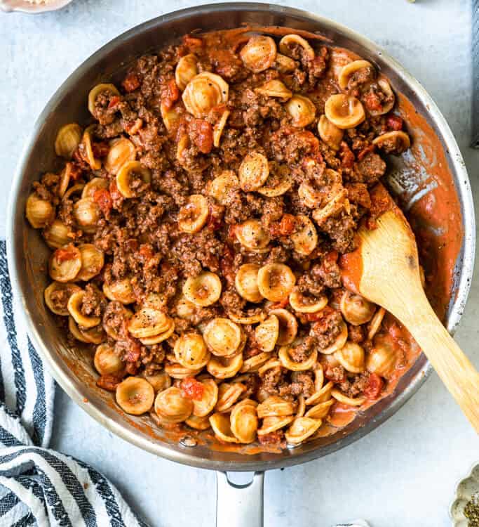 Tomato Orecchiette with Ground Beef in a skillet with a wooden spoon.