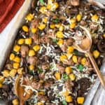 Sheet pan sausage and gnocchi on a sheet pan with wooden spoons.