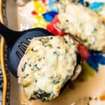 Spinach Artichoke Chicken on a baking sheet with a spatula.