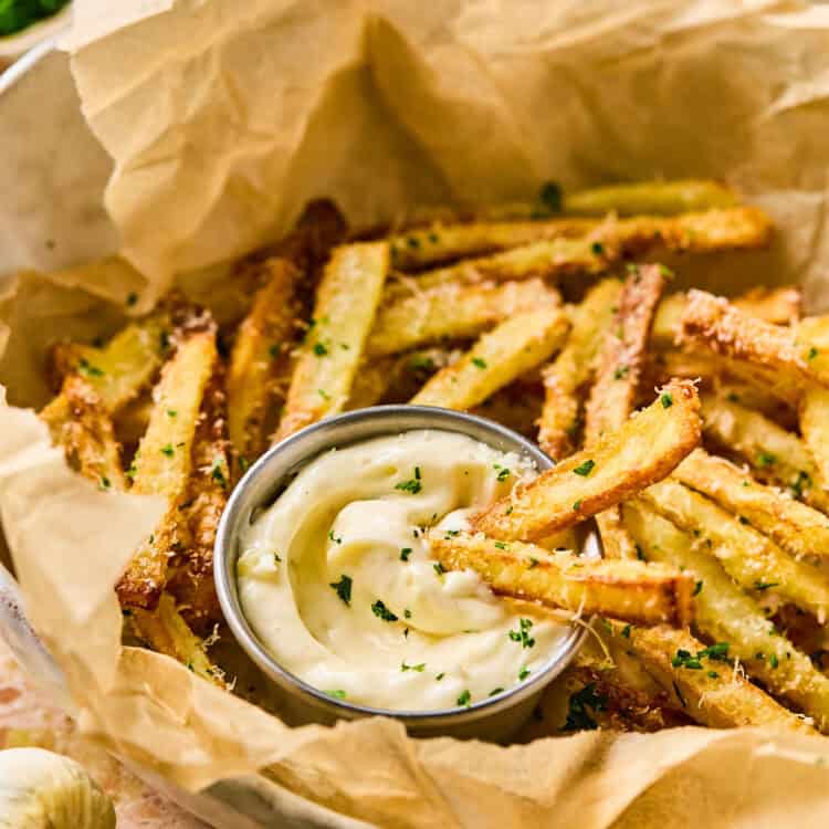 Garlic Parmesan Fries wit fry sauce in a basket with parchment paper.