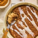Cinnamon Roll Pancake Bowl topped with glaze in a bowl with a spoon.