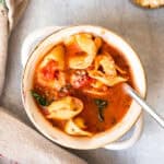 Creamy Tomato Tortellini Soup in a bowl with a spoon.