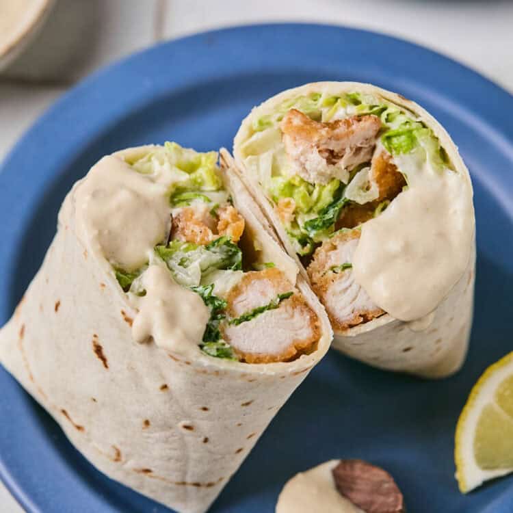 Breaded Chicken Caesar Wrap on a plate with lemon slices.