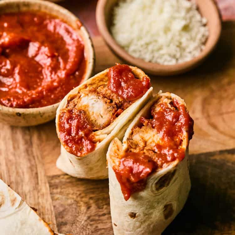 Chicken Parmesan Wrap sliced in half on a cutting board.