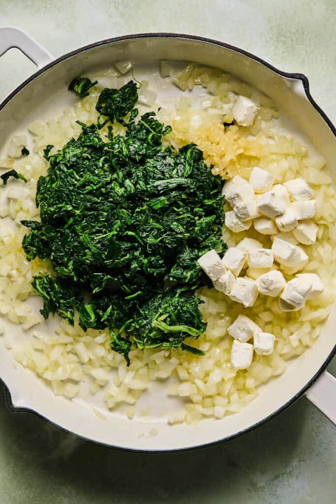 Olive oil, diced onion, and spinach in a skillet.