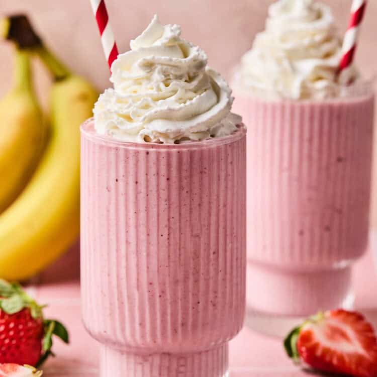 Strawberry Banana Oat Smoothie topped with whipped cream in a glass with a straw.