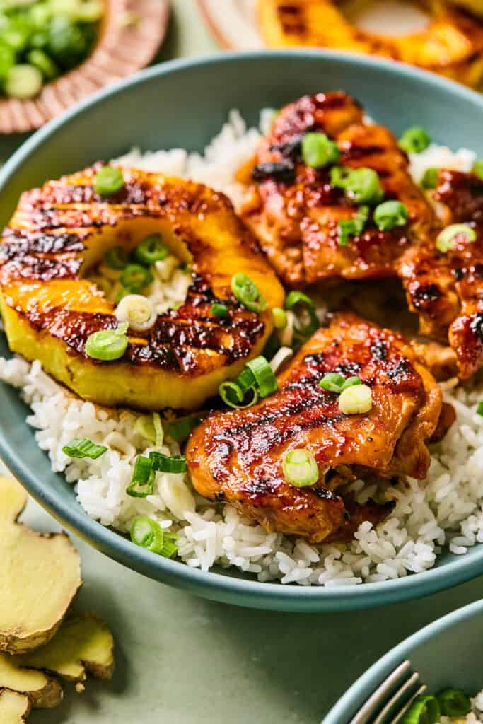 Huli Huli Chicken with pineapple rings over rice in a bowl.