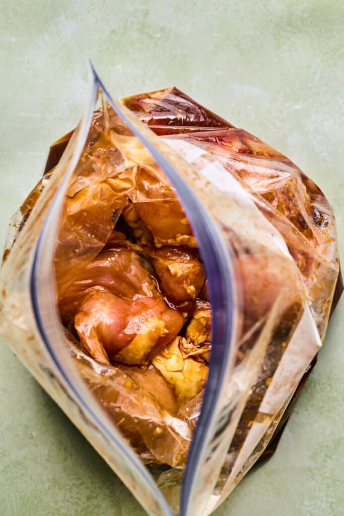 Chicken thighs with marinade in a large zip lock bag.