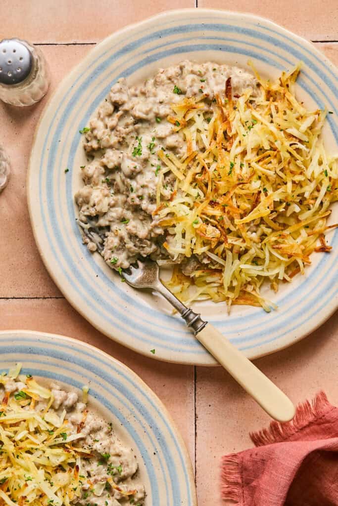 Homemade Turkey Sausage Gravy with hashbrowns on a plate with a fork.