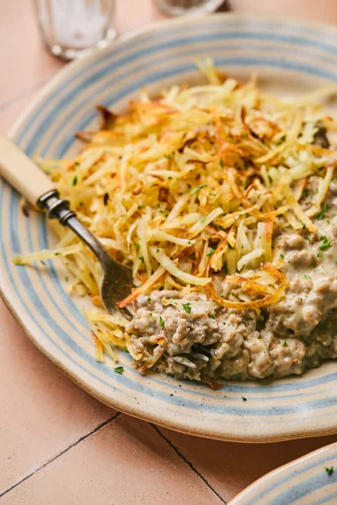 Homemade Turkey Sausage Gravy with hashbrowns on a plate with a fork.
