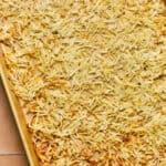 Hashbrowns spread out on a baking sheet after being browned.