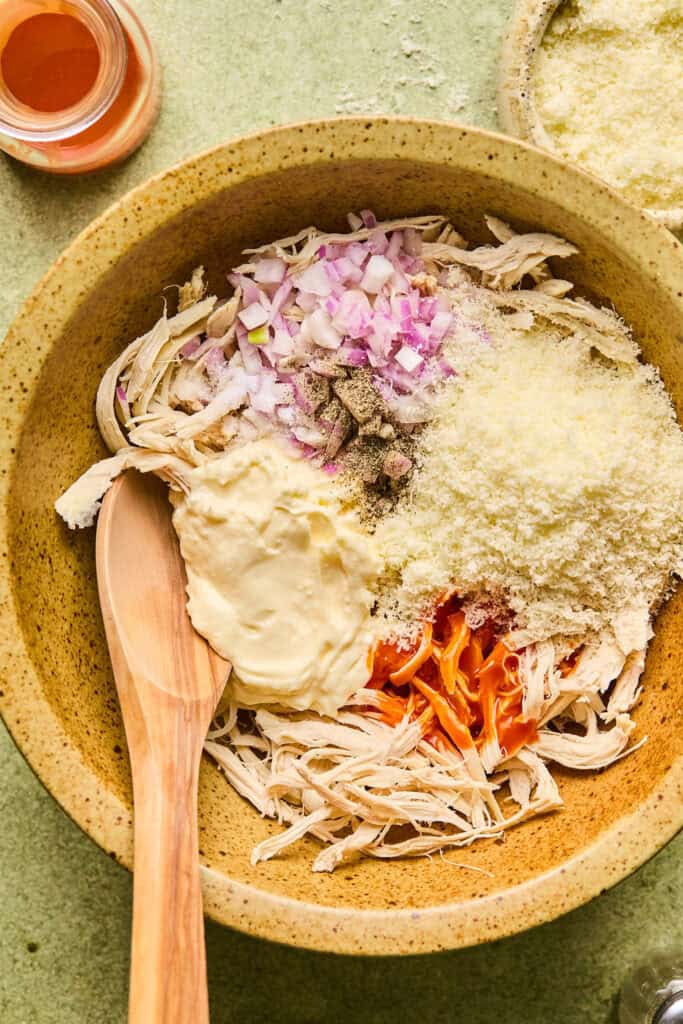 Ingredients for Buffalo Chicken Pinwheels in a bowl with a wooden spoon.