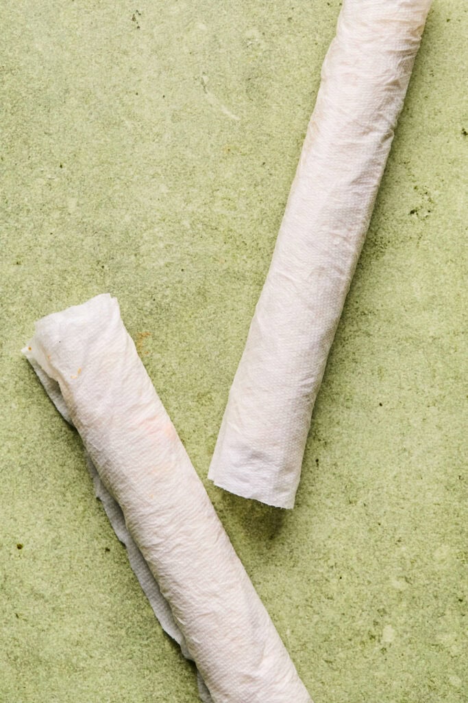 Two tortillas rolled up and covered with paper towel.