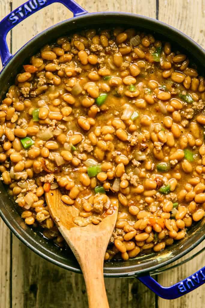 Cowboy Baked Beans in a pot with a wooden spoon.