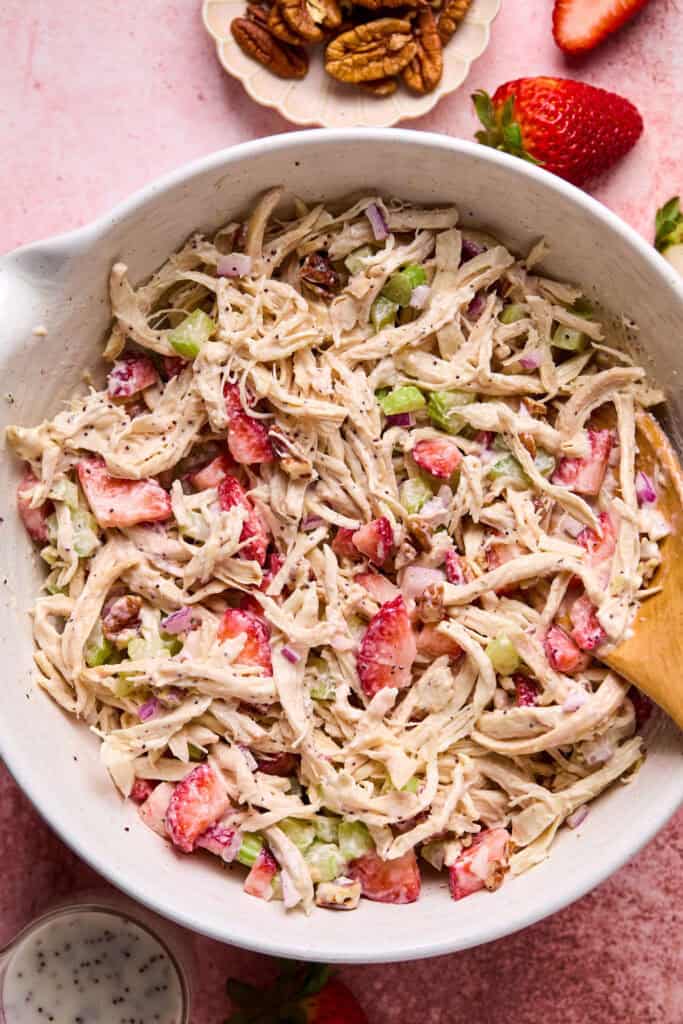Strawberry Poppyseed Chicken Salad in a bowl with a wooden spoon.
