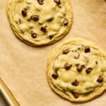 Two Huge Chocolate Chip Cookies on parchment paper.