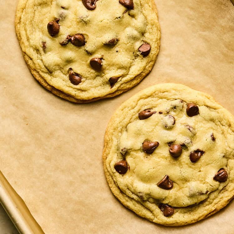 Two Huge Chocolate Chip Cookies on parchment paper.