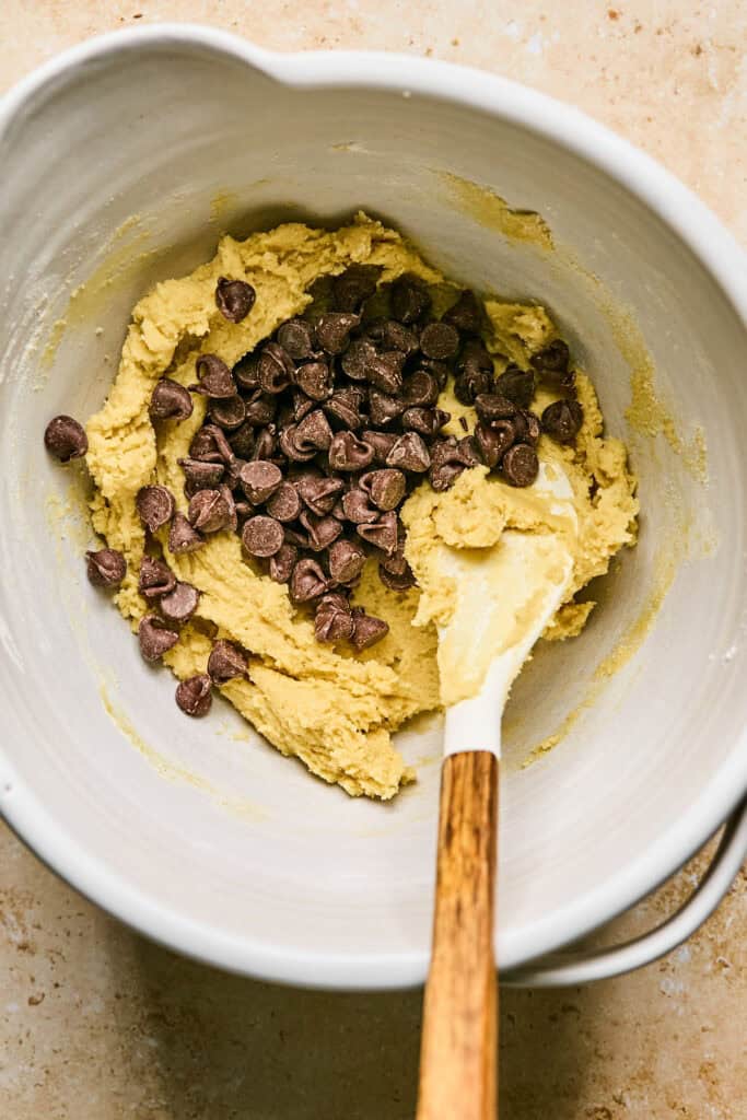 Chocolate chips added to the batter in a mixing bowl.