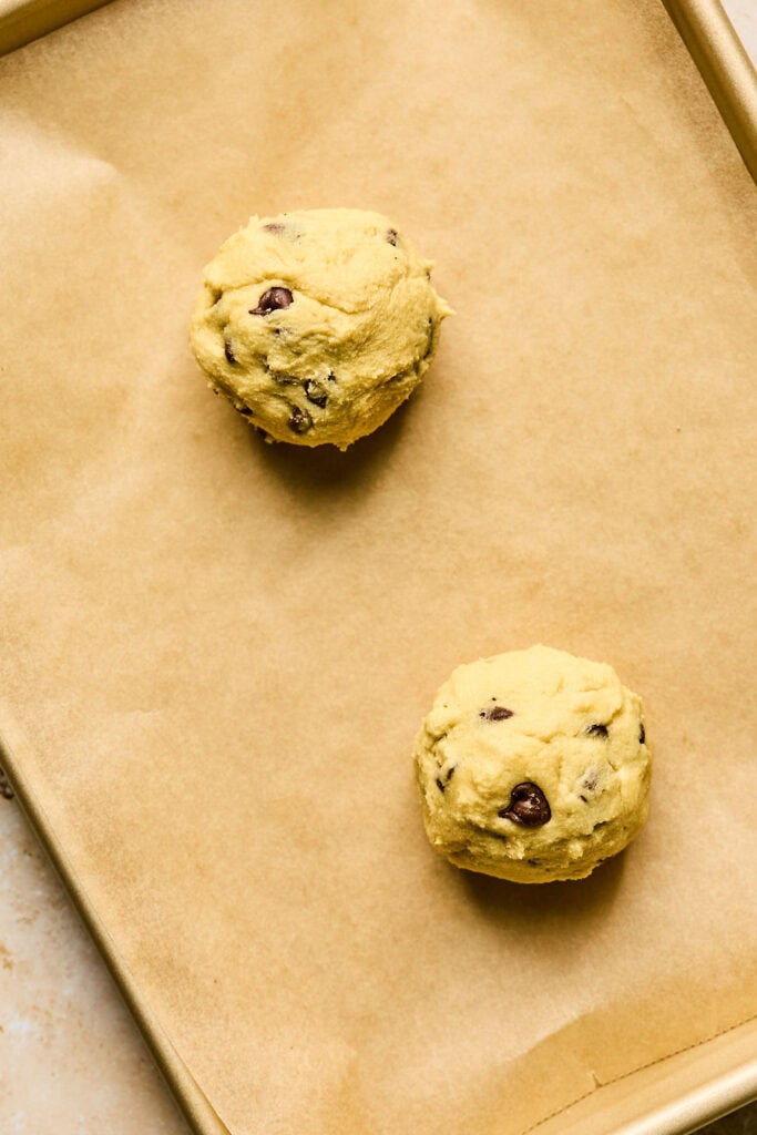 Two balls of cookie dough on parchment paper.