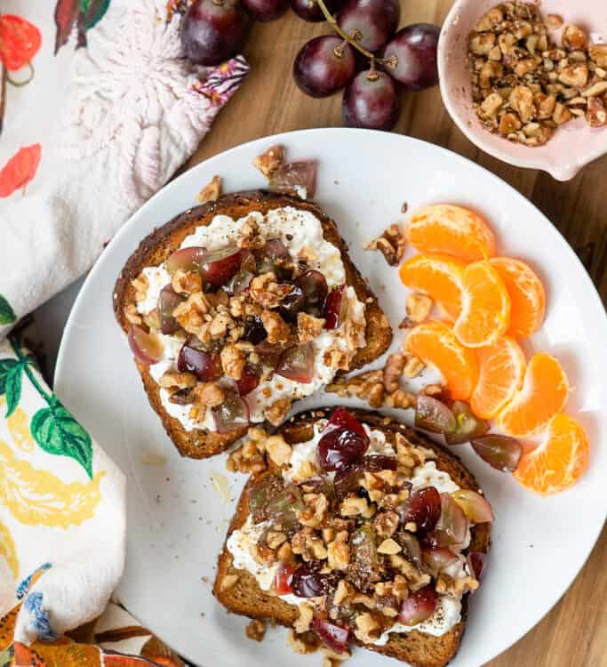 Grape and Walnut Cottage Cheese Toast with a side of clementines on a plate.