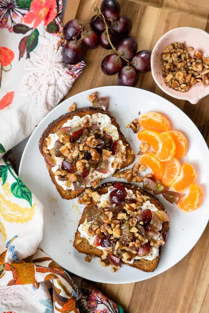 Grape and Walnut Cottage Cheese Toast with a side of clementines on a plate.