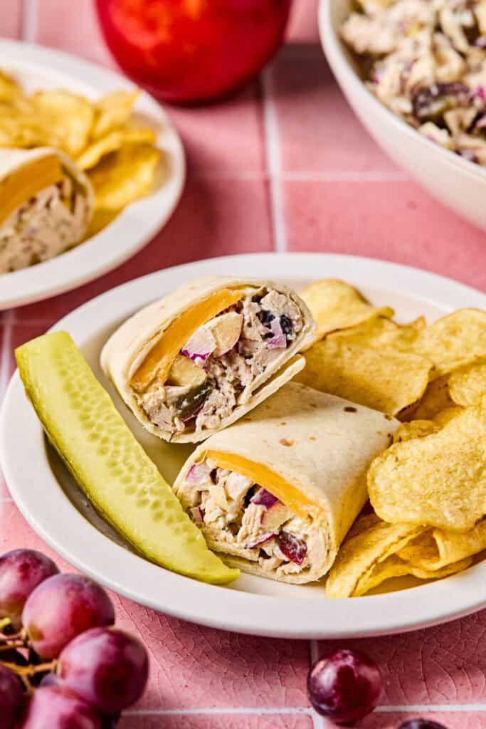 Apple Grape and Walnut Chicken Salad Wraps on a plate with chips and a pickle.