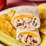 Apple Grape and Walnut Chicken Salad Wraps on a plate with chips and a pickle.