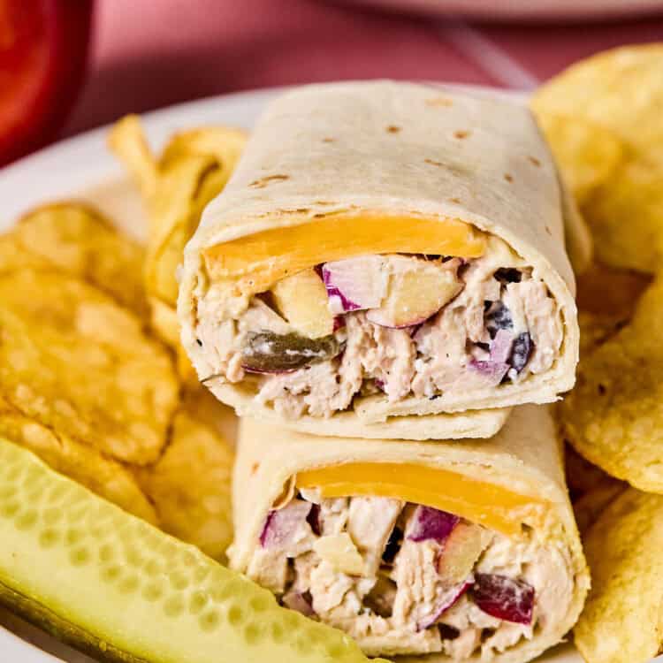 Apple Grape and Walnut Chicken Salad Wraps on a plate with chips and a pickle.
