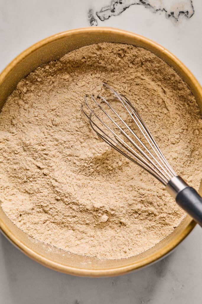 Dry ingredients for Maple Bacon Pancake Bake in a bowl with a whisk.