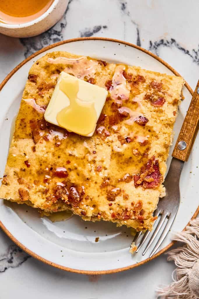 Maple Bacon Pancake Bake on a plate topped with butter and syrup.
