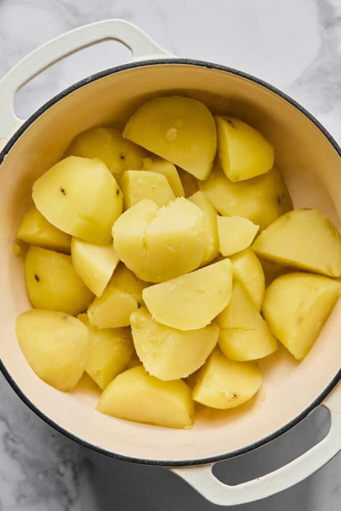 Peeled and quartered potatoes in a pot.