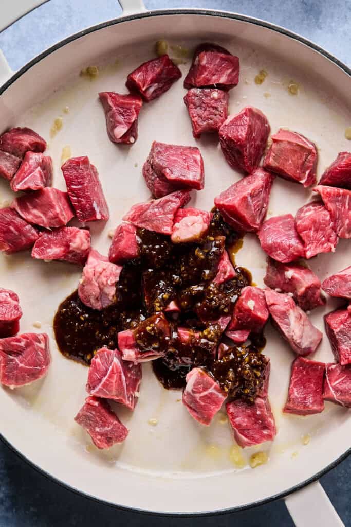 Uncooked steak bites with Hibachi Steak sauce in a skillet.