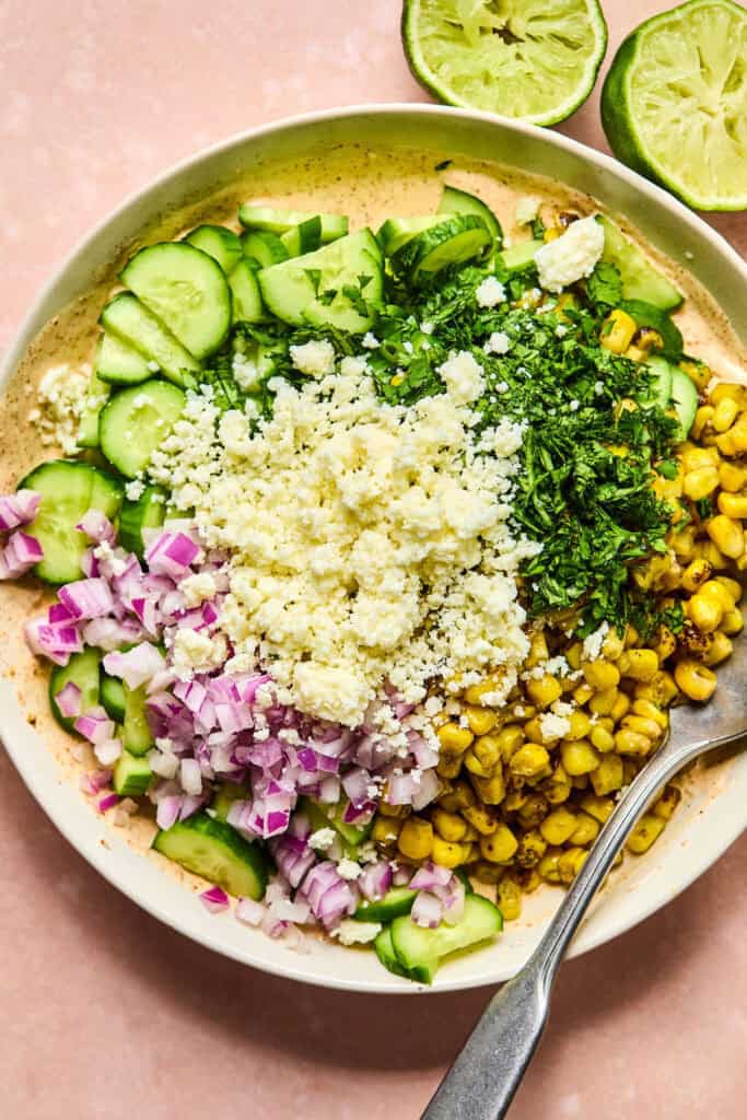 Ingredients for Mexican Cucumber Corn Salad in large bowl before being mixed together.