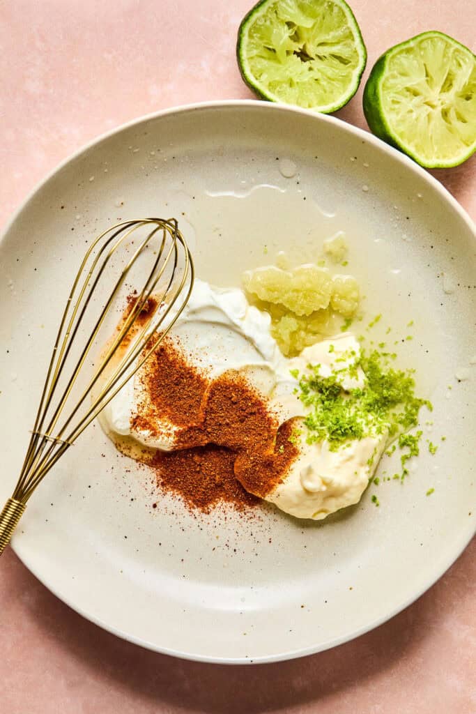 Dressing ingredients for Mexican Cucumber Corn Salad in a bowl with a whisk.