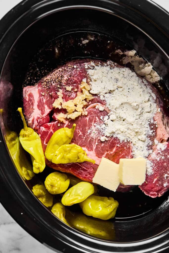 Ingredients for Mississippi Pot Roast in a slow cooker before being cooked.