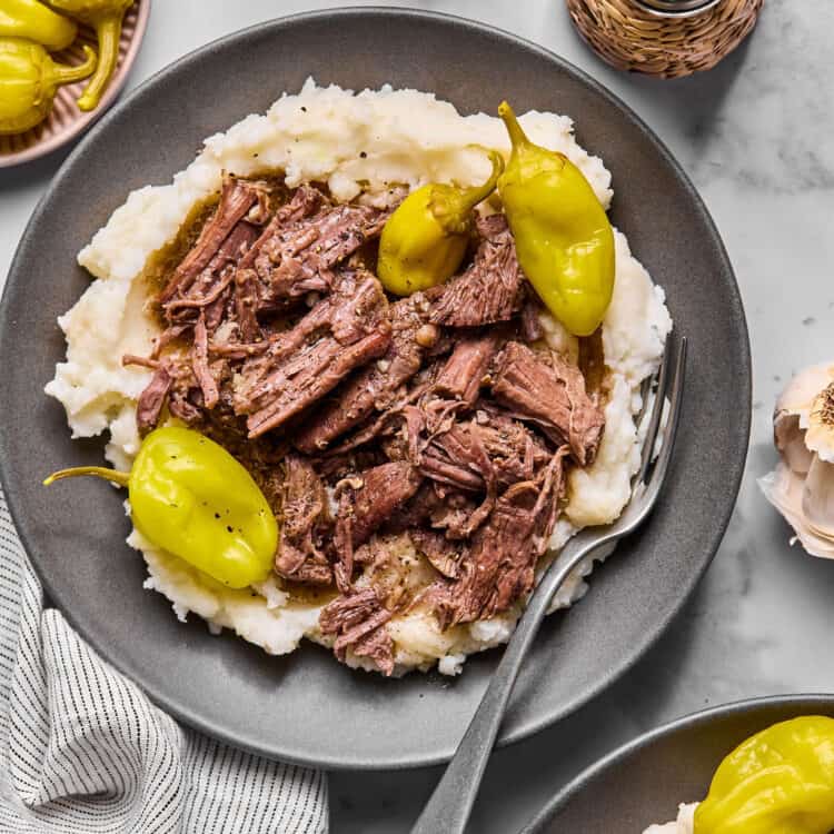 Mississippi Pot Roast over garlic mashed potatoes on a plate with a fork.