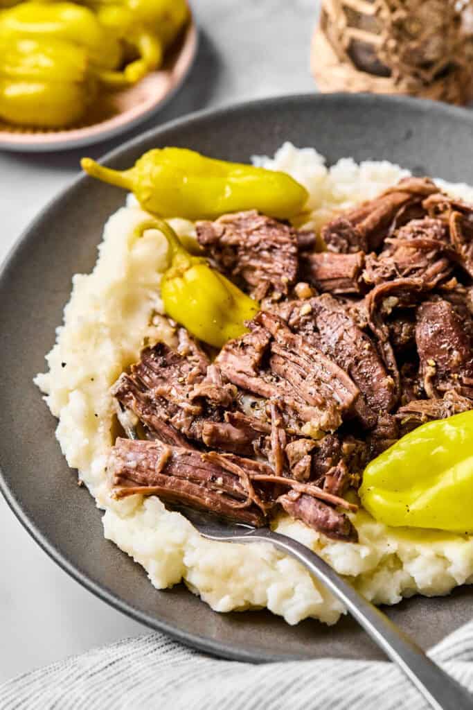 Mississippi Pot Roast with garlic mashed potatoes on a plate with a fork.