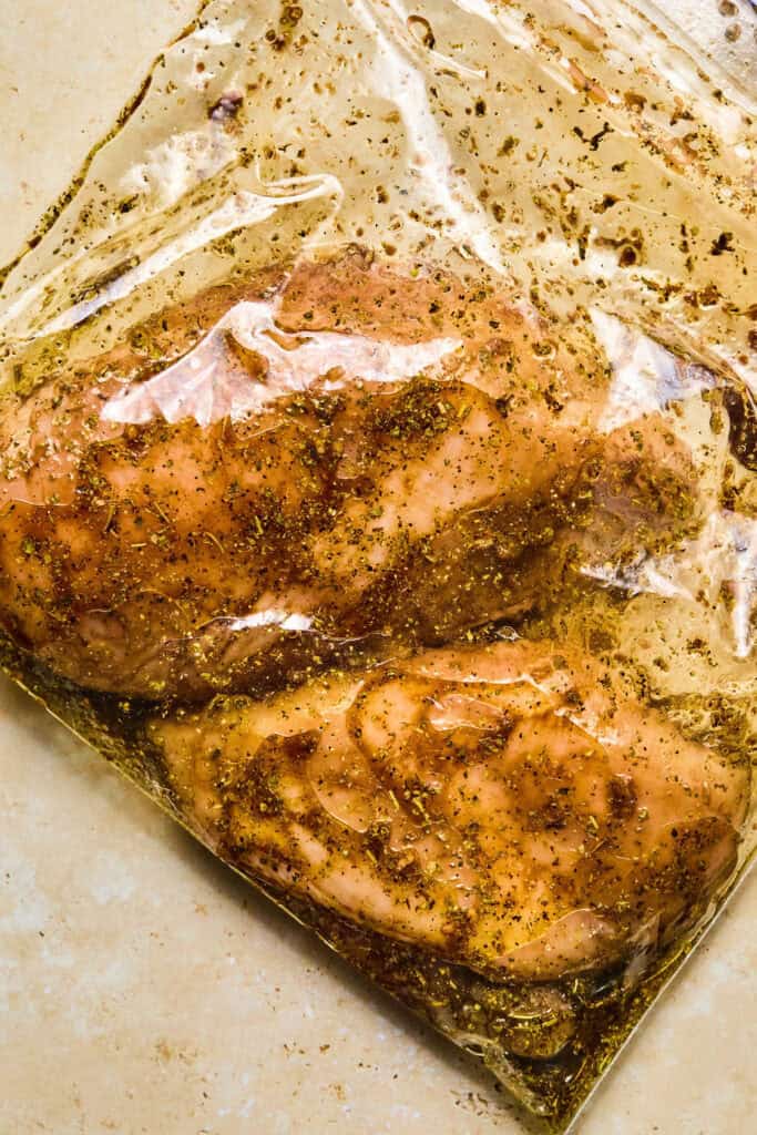 Raw chicken breasts with marinade in a zip lock bag.