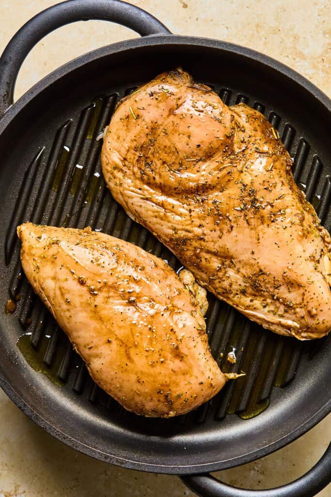 Two chicken breasts in a grill pan.