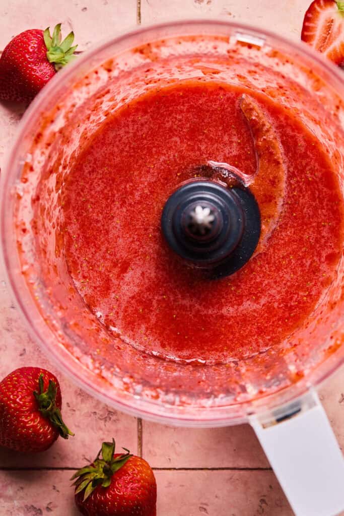 Strawberries and sugar puree in a food processor bowl.